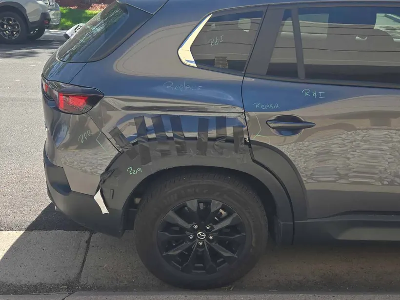 Mazda rear quarter taped up with estimator markings before repair